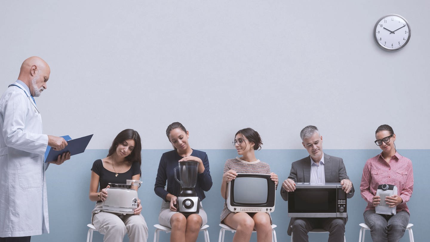 Mehrere Menschen sitzen wie im Wartezimmer beim Arzt nebeneinander und halten unterschiedliche kaputte Haushaltsgeräte auf dem Schoß: Mixer, Toaster, Mikrowelle und Fernseher. Ganz Links im Bild steht ein Arzt. Sollen die Elektrogeräte zur Reparatur oder zum Recycling?