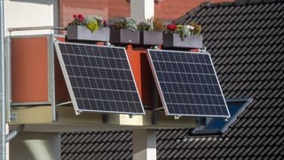 An einem Balkon sind zwei Solarmodule als Balkonkraftwerk befestigt.