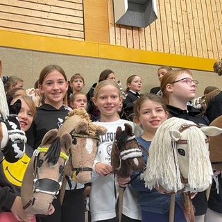 SchülerInnen auf Steckenpferden in einer Turnhalle