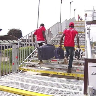 Flüchtlinge tragen Koffer eine Treppe hoch am Bahnhof