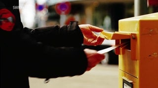 Nahaufnahme von einer Person, welche einen Brief in einen Briefkasten der Deutsche Post wirft