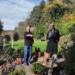 Ein Mann und eine Frau stehen in einem sonnigen Garten