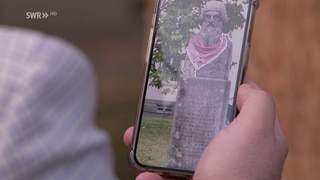 Ein Handy zeigt ein Bild der Gutenberg-Statue mit einer Küffiya