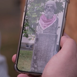 Ein Handy zeigt ein Bild der Gutenberg-Statue mit einer Küffiya