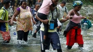 Migrantinnen und Migranten überqueren einen Fluss im Darién-Dschungel