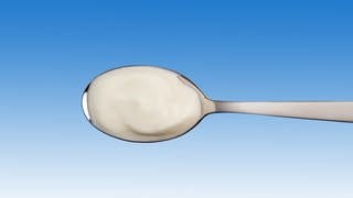 Joghurt auf Löffel: Probiotische Lebensmittel können die Therapie von Patienten mit Darmproblemen unterstützen