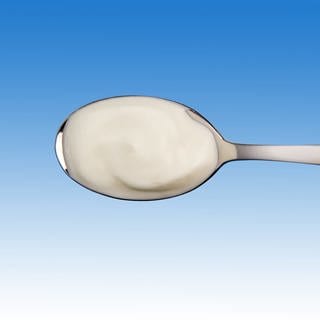 Joghurt auf Löffel: Probiotische Lebensmittel können die Therapie von Patienten mit Darmproblemen unterstützen