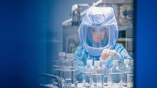 Mit Ganzkörper-Schutzanzügen simulieren Laborantinnen der Firma Biontech in einem Reinraum am neuen Produktionsstandort in Marburg die finalen Arbeitsschritte zur Herstellung des Corona-Impfstoffes an einem Bioreaktor. 