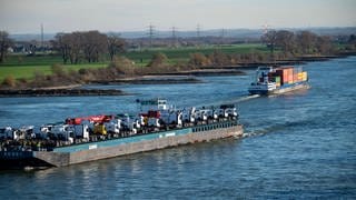 Frachtschiff auf dem Rhein bei Krefeld: Flüsse wie der Rhein fließen auch in der Ebene schnell. Der Grund ist der geringe Reibungswiderstand im Wasser. Und je weiter weg vom Ufer und je tiefer das Flussbett, desto schneller fließt das Wasser. 