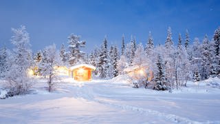 Beleuchtete Hütte in weißer Winterlandschaft: Schnee ist weiß, obwohl Wasser durchsichtig ist
