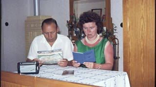 Ehepaar bei der Urlaubsplanung um 1970: Das Postsparbuch gehört auch dazu