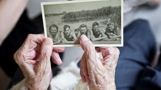 Alte Damenhände halten ein historisches Erinnerungsfoto aus den 1940ern: Die Fähigkeit, aktuelle Geschehnisse abzuspeichern, wird im Alter schlechter. Daher hat in der Beurteilung von Situationen das, was wir schon mal erlebt und gelernt haben, ein stärkeres Gewicht.