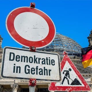 Schild vor der Reichstagskuppel "Demokratie in Gefahr": Deutsche Rechtsextreme und Islamisten nähern sich – trotz großer ideologischer Unterschiede – immer wieder an. Entstehen hier neue Bündnisse? Wie gefährlich ist das für Deutschland?