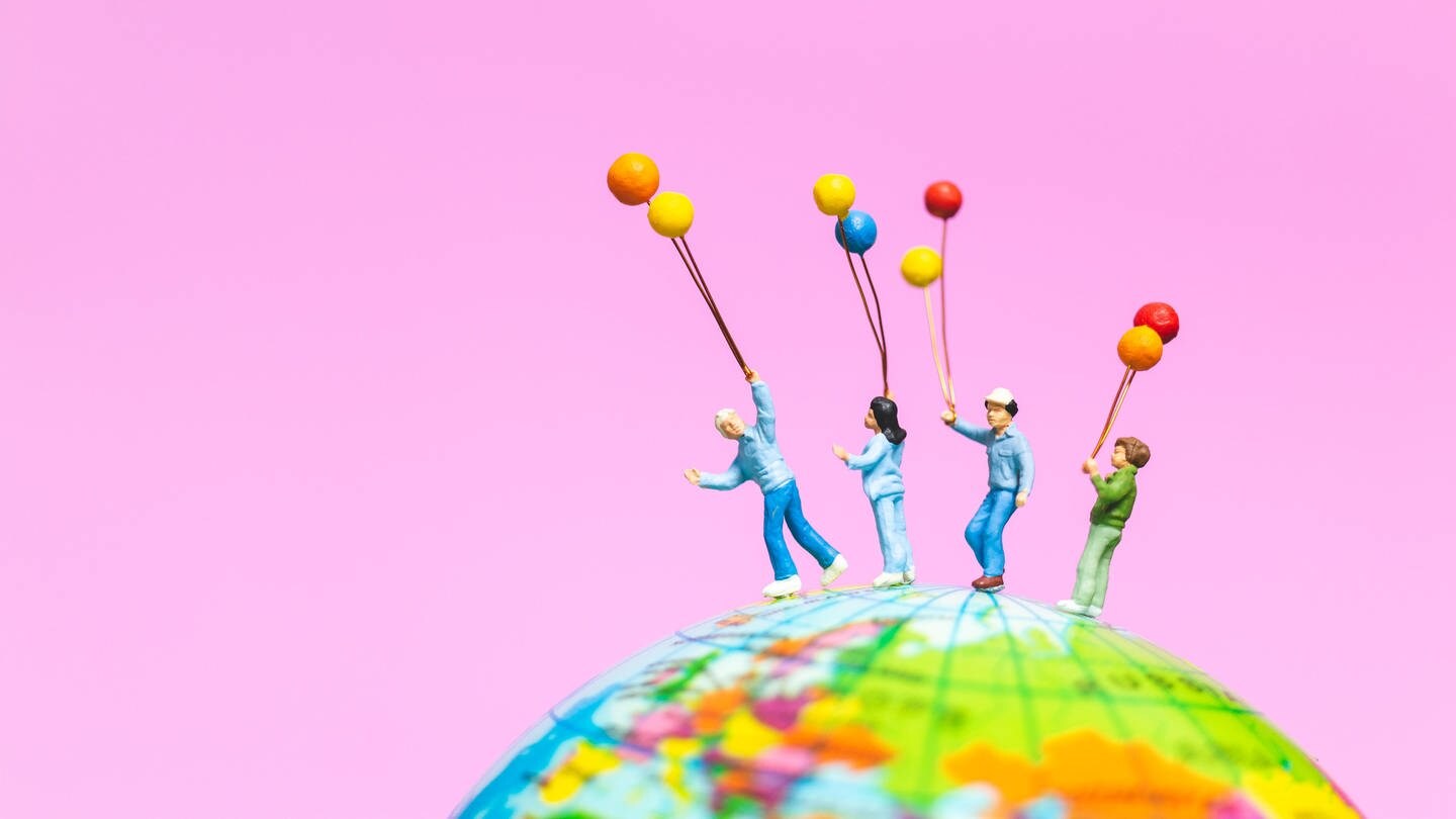 Miniaturfiguren stehen auf einem Globus: Wie groß müsste die Erdkugel sein, damit alle Menschen dort einen Stehplatz hätten?