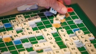 Ein Scrabble-Spieler legt ein neues Wort aufs Spielbrett: Intelligenz ist an Symbole gebunden. Sprache ist ein Symbol. Und ohne die Fähigkeit, Symbole zu haben, könnten wir nicht die Intelligenz zeigen, die wir haben. 