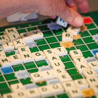 Ein Scrabble-Spieler legt ein neues Wort aufs Spielbrett: Intelligenz ist an Symbole gebunden. Sprache ist ein Symbol. Und ohne die Fähigkeit, Symbole zu haben, könnten wir nicht die Intelligenz zeigen, die wir haben. 