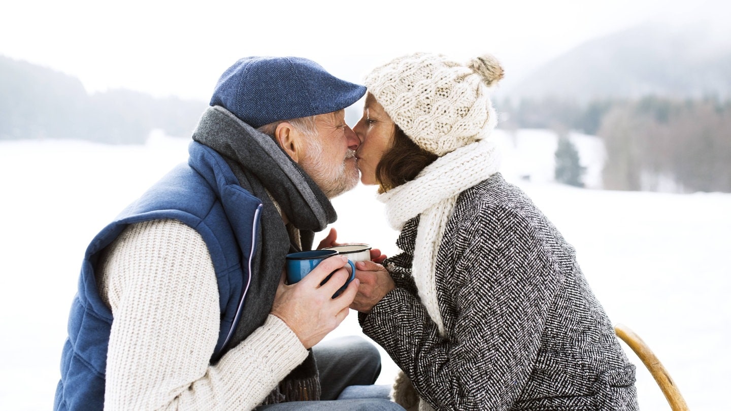 Älteres Paar küsst sich im Schnee: Vieles spricht dafür, dass der Kuss vor allem eine sexuelle Signalfunktion hat; er bringt ein intimes Verhältnis zum Ausdruck.