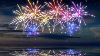 Feuerwerk in rot und blau: Rotes und blaues Licht unterscheiden sich in der Energiedichte, sie befinden sich jeweils auf den entgegengesetzten Seiten des Regenbogens. Blaues Licht schwingt fast doppelt so schnell wie rotes und hat eine entsprechend kürzere Wellenlänge. Und weil es schneller schwingt, sind die Lichtteilchen auch energiereicher. Trotzdem wirkt rotes Licht wärmer.