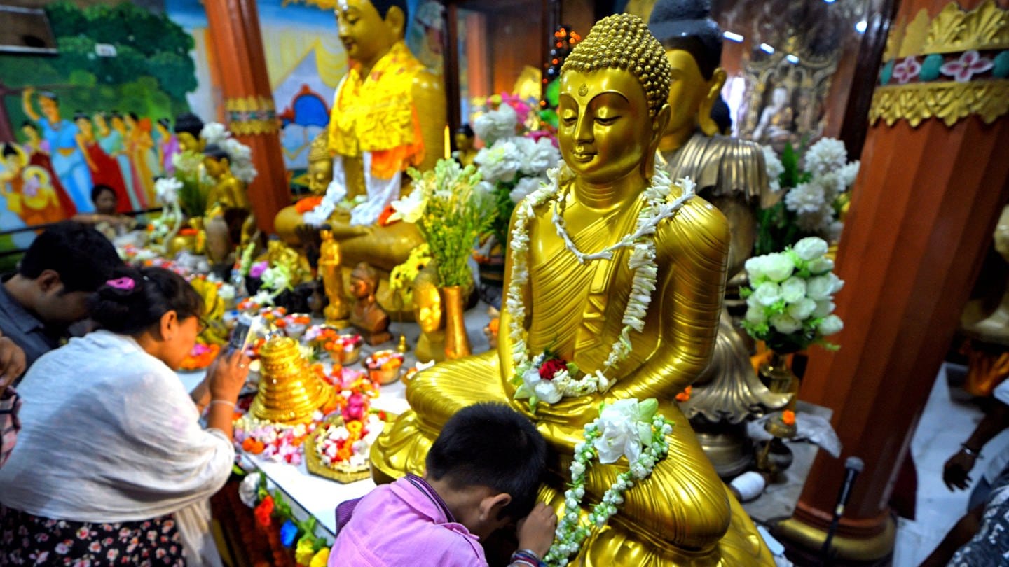 Buddhisten beim Gebet vor einer Buddha-Statue