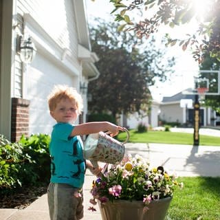 Ein Junge gießt Blumen in der Sonne