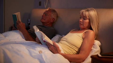 Ein Ehepaar liegt abends im Bett und liest.