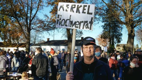 Demonstration gegen Corona-Maßnahmen des Querdenken-Bündnisses in Aichach, Bayern, im November 2020, ein Mann steht vereinzelt und trägt ein Schild mit der Aufschrift: "Merkel Hochverrat"