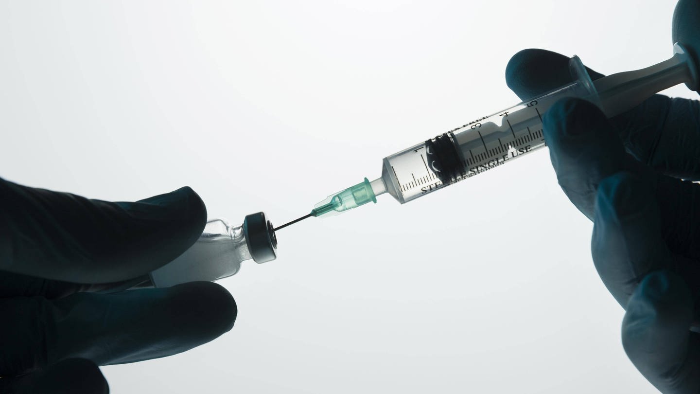 Das Bild zeigt eine Impfspritze, die aufgezogen wird.
