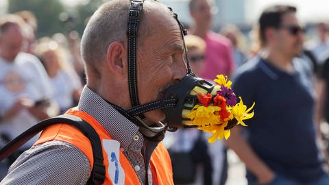 Mann trägt skurrile Gesichtsmaske mit Blumen, Demo gegen Corona-Regeln auf den Düsseldorfer Rheinwiesen