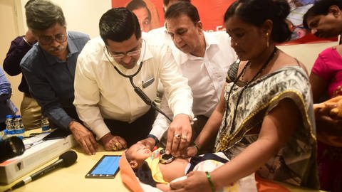 Ein Arzt in Indien untersucht einen Säugling auf Herzprobleme.
