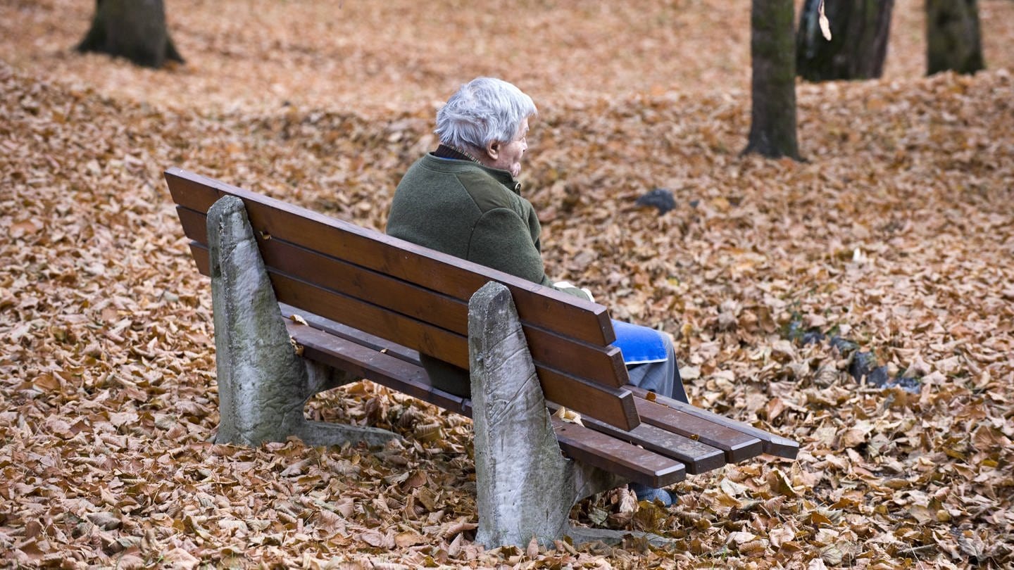 Senior sitzt auf einer Bank im Park