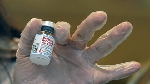 Person mit Moderna Impfstoff in der Hand