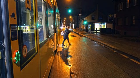 Frau steigt im Dunkeln aus Straßenbahn