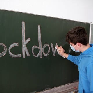 Schüler wischt "Lockdown"-Aufschrift von Tafel