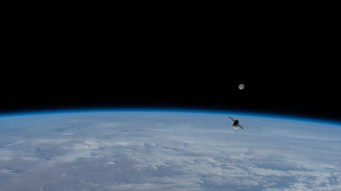 Internationale Raumstation ISS mit einem Ausschnitt der gekrümmten Erde im Hintergrund.