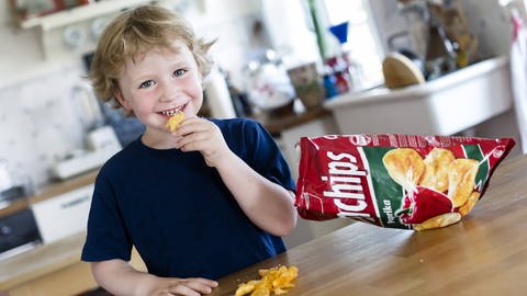 Kleiner Junge, 4 Jahre, isst Chips.