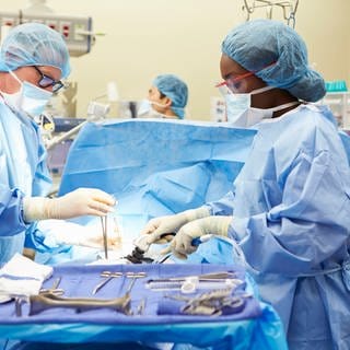 Ein Chirurg und eine Chirurgin stehen im OP und operieren einen Patienten 