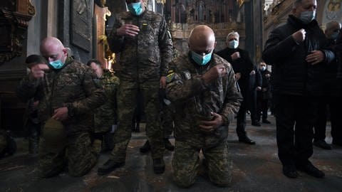 Soldaten und Einwohner beten während der russischen Invasion in die Ukraine.