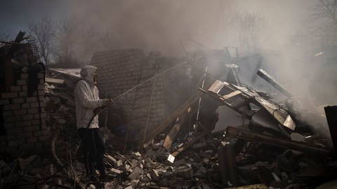 Nachbarn versuchen das Feuer eines Hauses zu löschen, das nach einem russischen Angriff in Charkiw zerstört wurde.