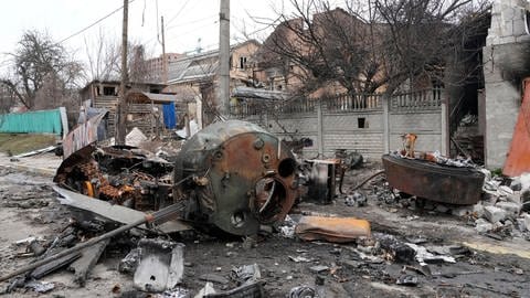 Ein zerstörtes russisches Militärfahrzeug steht in Butscha auf einer Straße.