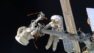 Andre Kuipers fängt seine russischen Besatzungsmitglieder bei einem Weltraumspaziergang außerhalb der Internationalen Raumstation ein.