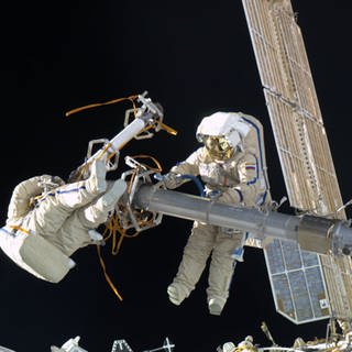 Andre Kuipers fängt seine russischen Besatzungsmitglieder bei einem Weltraumspaziergang außerhalb der Internationalen Raumstation ein.
