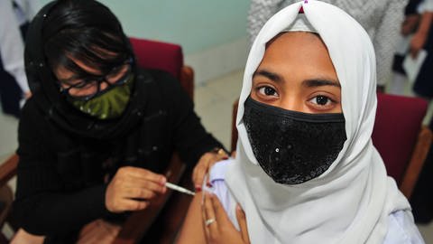 Eine Schülerin aus Bangladesh bekommt ihre BioNtech Pfizer Impfung.