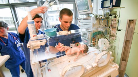 Kinderkrankenpfleger künmmern sich um ein Baby.