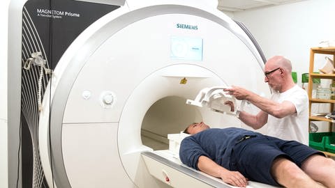 Arzt legt Patienten eine Kopfspule an einem Magnetresonanztomograph (MRT) an.