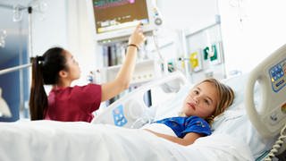 Das Bild zeigt ein Mädchen, das in einem Krankenhaus behandelt wird und an ein Sauerstoffgerät angeschlossen ist.