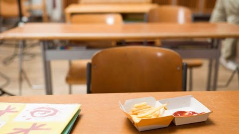 Schachtel Pommes mit Ketchup auf einem Tisch in der Schule