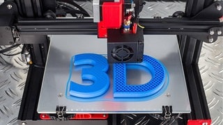 Ein 3D-Drucker druckt die Zahl "3" und den Buchstaben "D" in blauem Plastik.