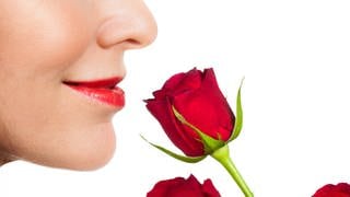 Eine Frau riecht an einer roten Rose