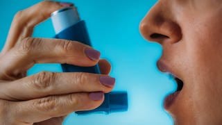 Frau mit Asthma nutzt einen Inhalator