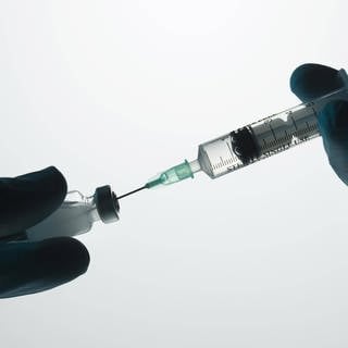 Das Bild zeigt eine Impfspritze, die aufgezogen wird.